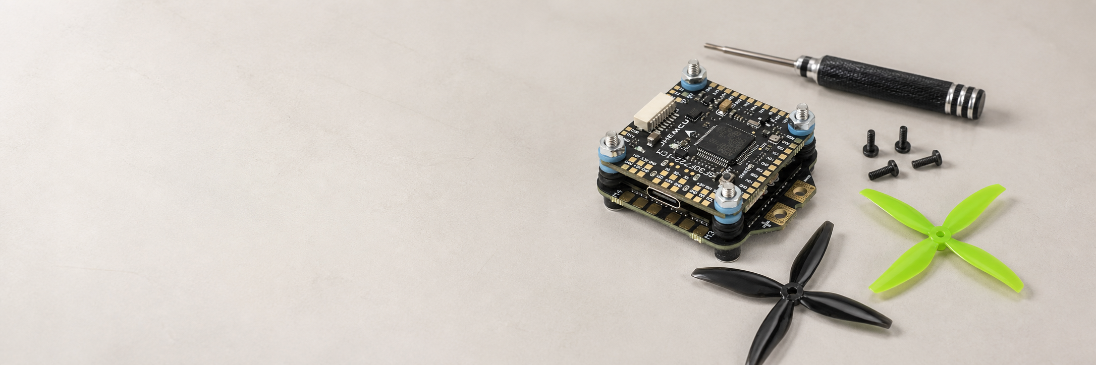 FPV flight controller stack, propellers and tools on a clean workbench