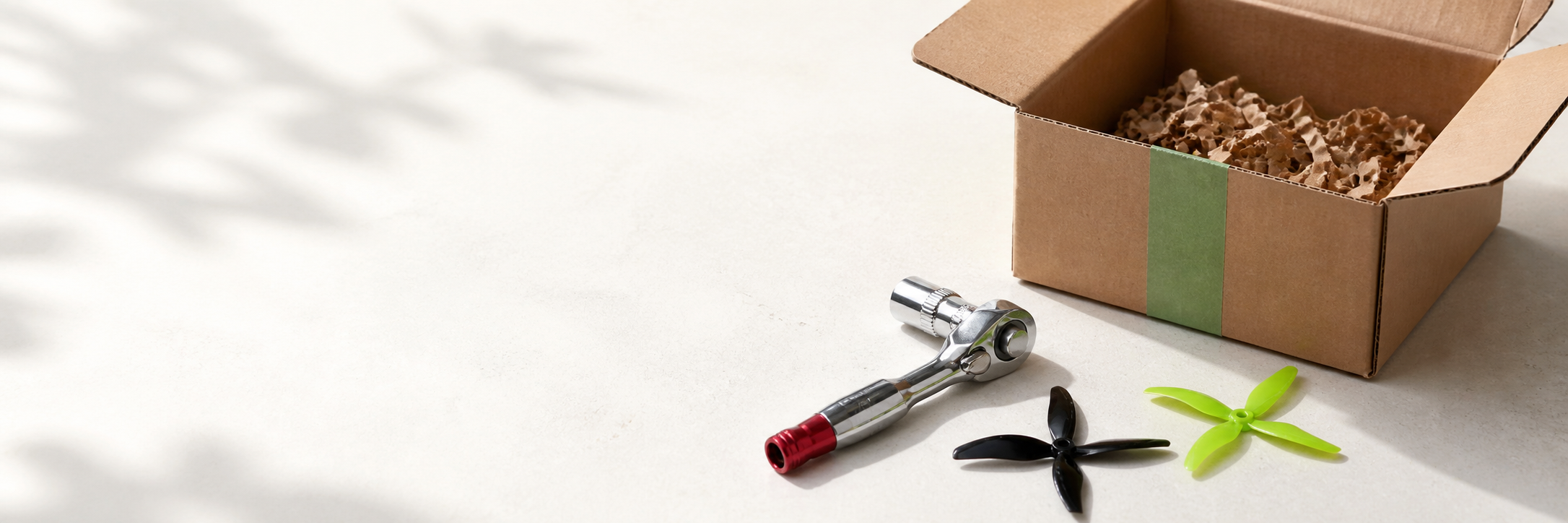 FPV propellers and ratchet tool beside a packed shipping box